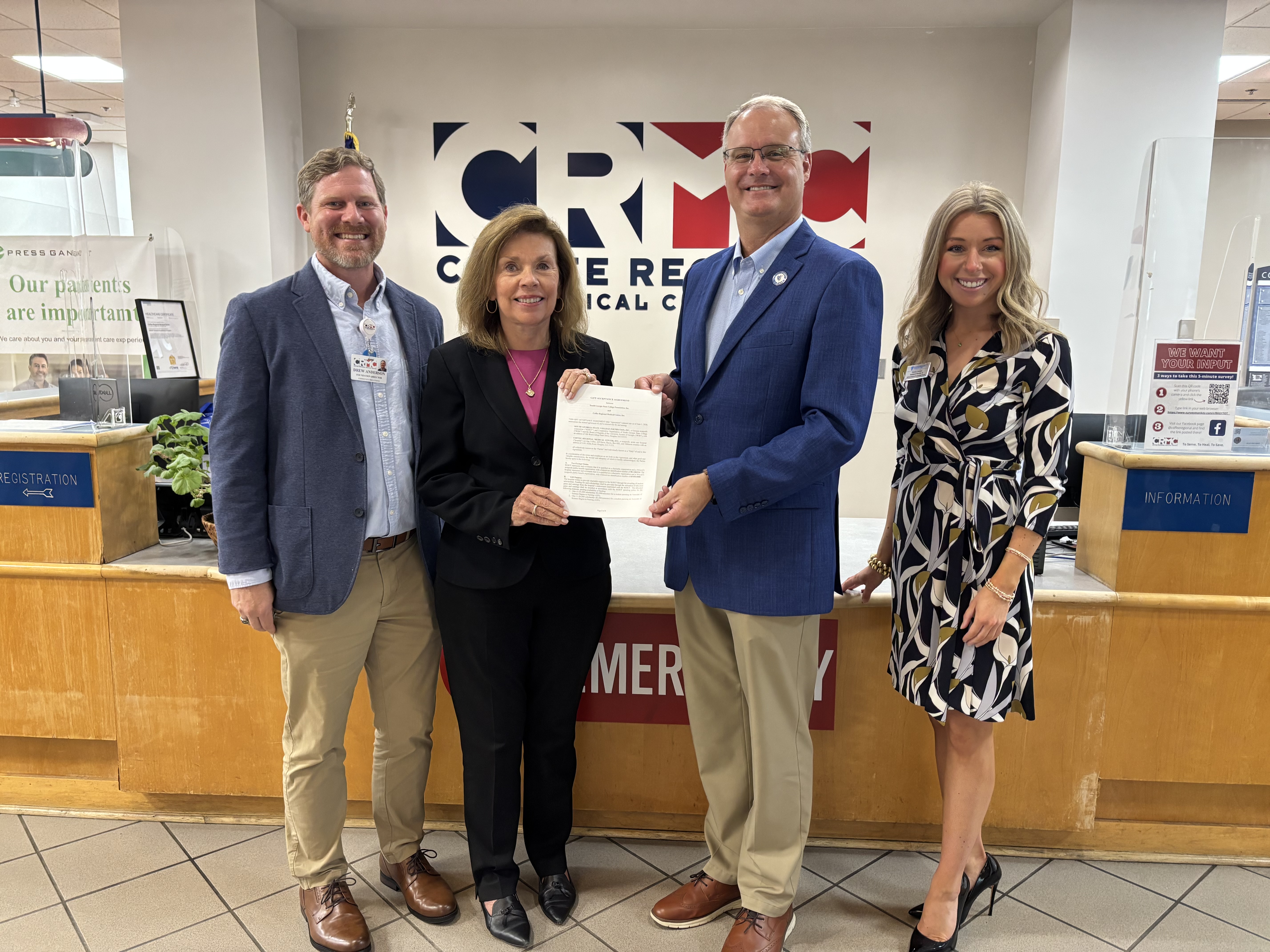 Four people in front of CRMC sign holding an agreement